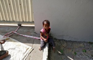 Barrier tape is tied around 15-month-old Shivani's ankle to prevent her from running away, while her mother Sarta Kalara works at a construction site nearby, in Ahmedabad, India, April 20, 2016. Kalara says she has no option but to tether her daughter Shivani to a stone despite her crying, while she and her husband work for 250 rupees ($3.8) each a shift digging holes for electricity cables in the city of Ahmedabad. There are about 40 million construction workers in India, at least one in five of them women, and the majority poor migrants who shift from site to site, building infrastructure for India's booming cities. Across the country it is not uncommon to see young children rolling in the sand and mud as their parents carry bricks or dig for new roads or luxury houses. REUTERS/Amit Dave SEARCH "TIED TODDLER" FOR THIS STORY. SEARCH "THE WIDER IMAGE" FOR ALL STORIES