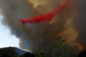 A water bomber makes a drop as firefighters battle a wildfire in temperatures well over 100F as it burns near Potrero, California