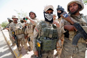 Iraqi army soldiers stand with their weapons in center of Falluja