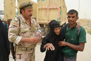 An Iraqi soldier helps civilians, who fled from Falluja because of Islamic State violence, during a dust storm on the outskirts of Falluja