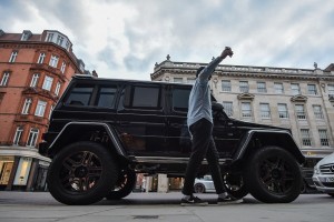 A man takes a selfie as he walks past a raised Mercdes-Benz on Sloane Street in London, England on August 09 2016.