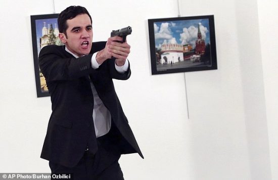 ADDS THE NAME OF THE GUNMAN - A man identified as Mevlut Mert Altintas holds up a gun after shooting Andrei Karlov, the Russian Ambassador to Turkey, at a photo gallery in Ankara, Turkey, Monday, Dec. 19, 2016. Shouting "Don't forget Aleppo! Don't forget Syria!" Altintas fatally shot Karlov in front of stunned onlookers at a photo exhibit. Police killed the assailant after a shootout. (AP Photo/Burhan Ozbilici)