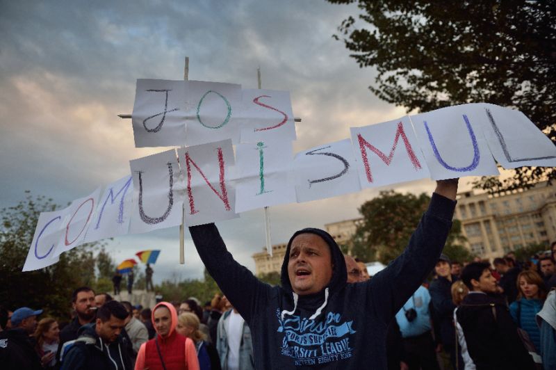 Protestuesi mban në dorë një pankartë që shkruan "Poshtë Komunizmi"